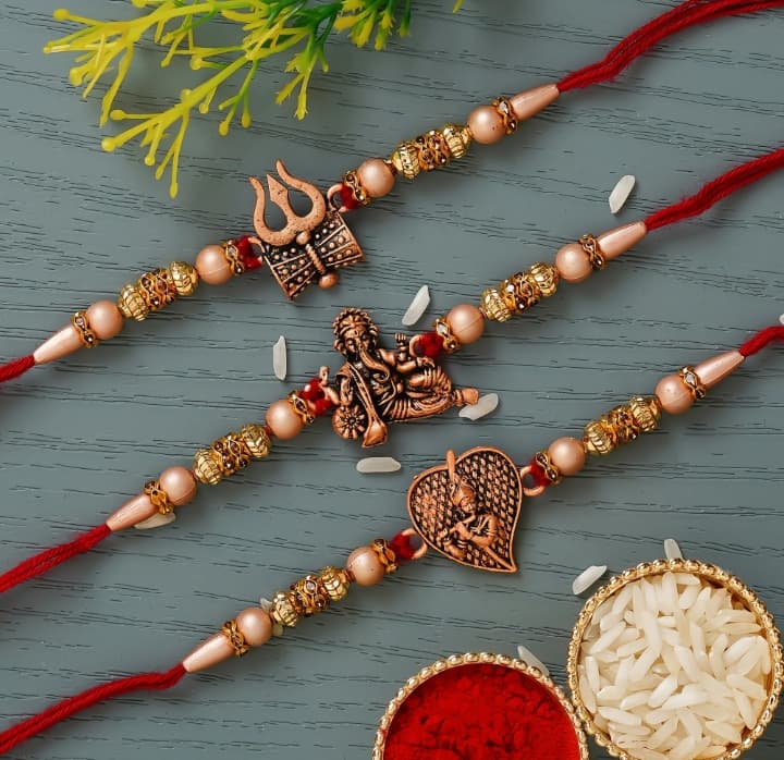 Red & Golden Set of 3 Trishul with Damru, Lord Ganesha, & Lord Krishna Playing Flute Religious Rakhis with Roli Chawal Pack